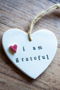 A white clay heart-shaped ornament that says I am grateful to remind us to practice gratitude.