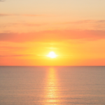 Sun rising above the horizon over the ocean reminds us of the Fresh Start Effect of a new day.